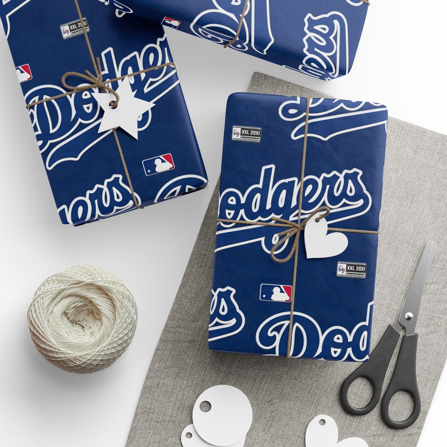 Gift wrap with Los Angeles Dodgers branding on a white surface with scissors and twine.
